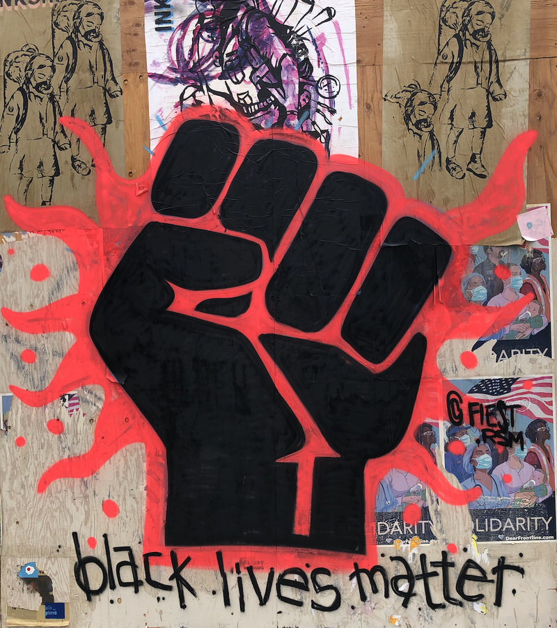 Graffiti style artwork of a black first with red lines of energy running through it with the words "black lives matter" underneath