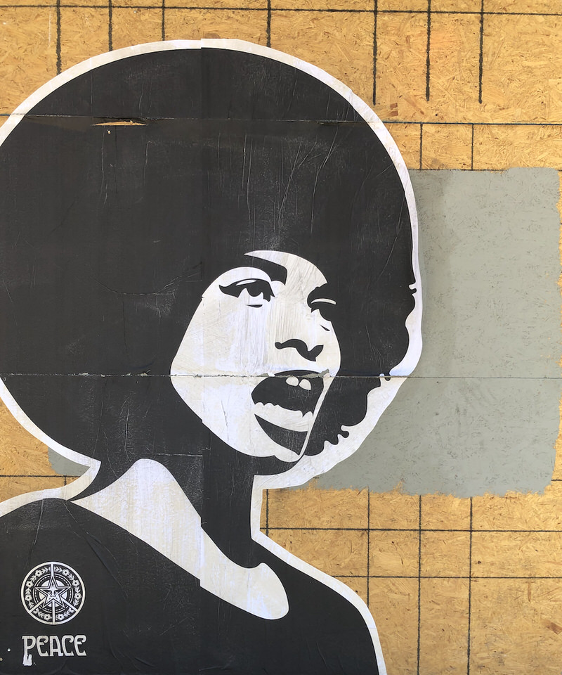 A large black-and-white image on a plywood barrier of a woman of color speaking