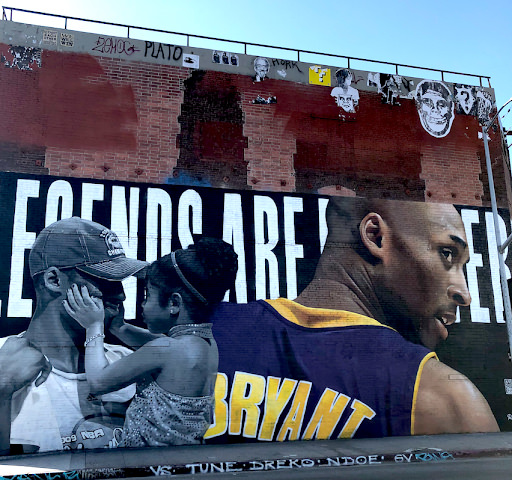 A large mural of Kobe Bryant in his Lakers jersey, next to an image of him holding his daughter, painted over the words LEGENDS ARE FOREVER.