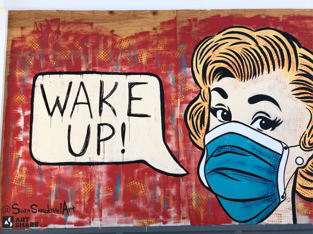 A vintage-style illustration of a woman in a mask, a cartoon speech bubble coming from her mouth with the words, "WAKE UP!"