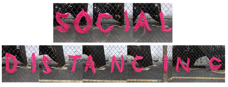 The words SOCIAL DISTANCING crocheted in pink across a long stretch of fence