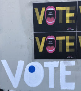 A wall with posters and hand-painted art that read "VOTE"