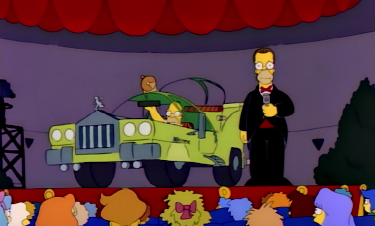 Homer sits in a bizarre looking green car while Herb stares out in embarrassment